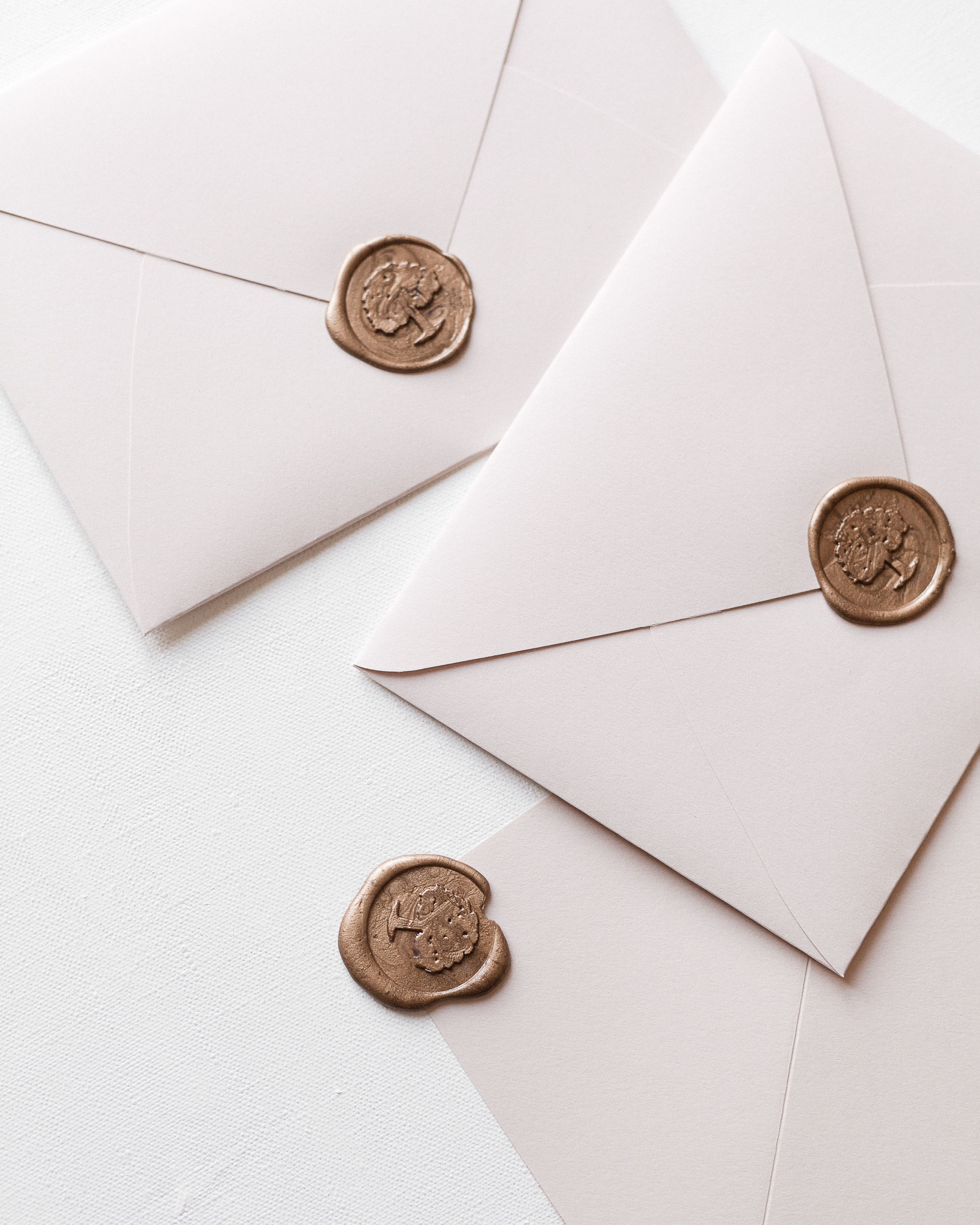 Two cream envelopes with gold wax seals.
